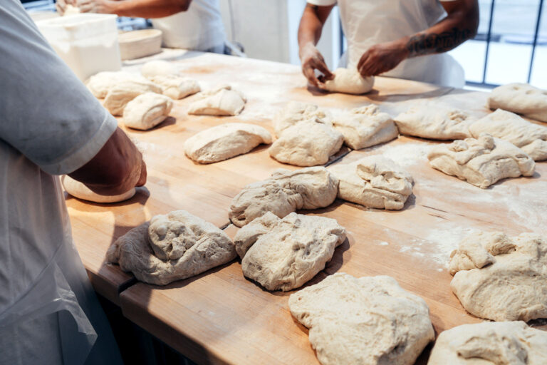 a photo of bakers rolling dough